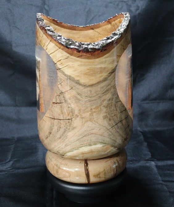 Wooden carved vase with a natural edge, on a black base.