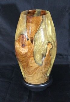 Wooden vase with swirling grain patterns encased in a yellowish resin, set on a black base.