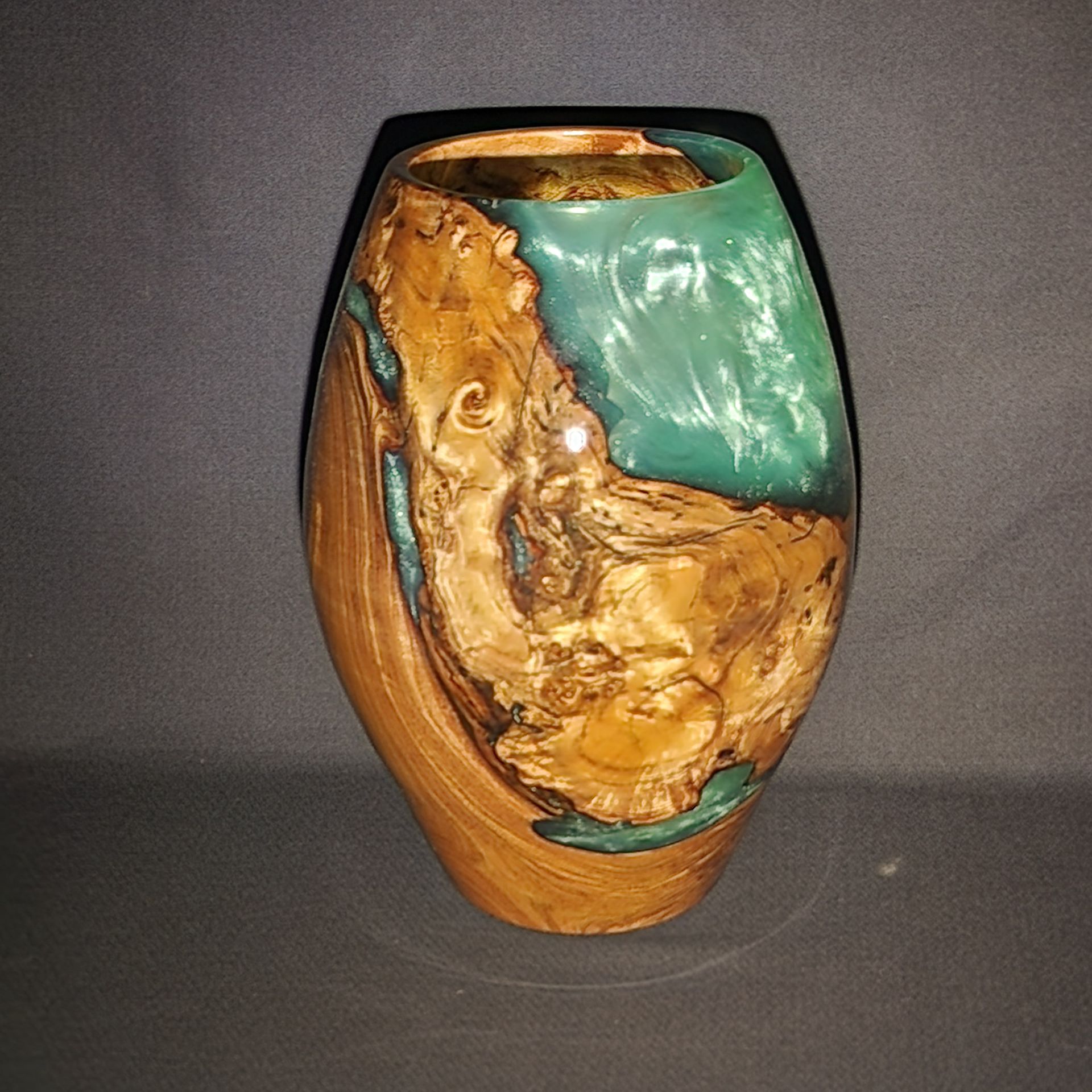 Wooden vase with teal resin filling natural wood voids.