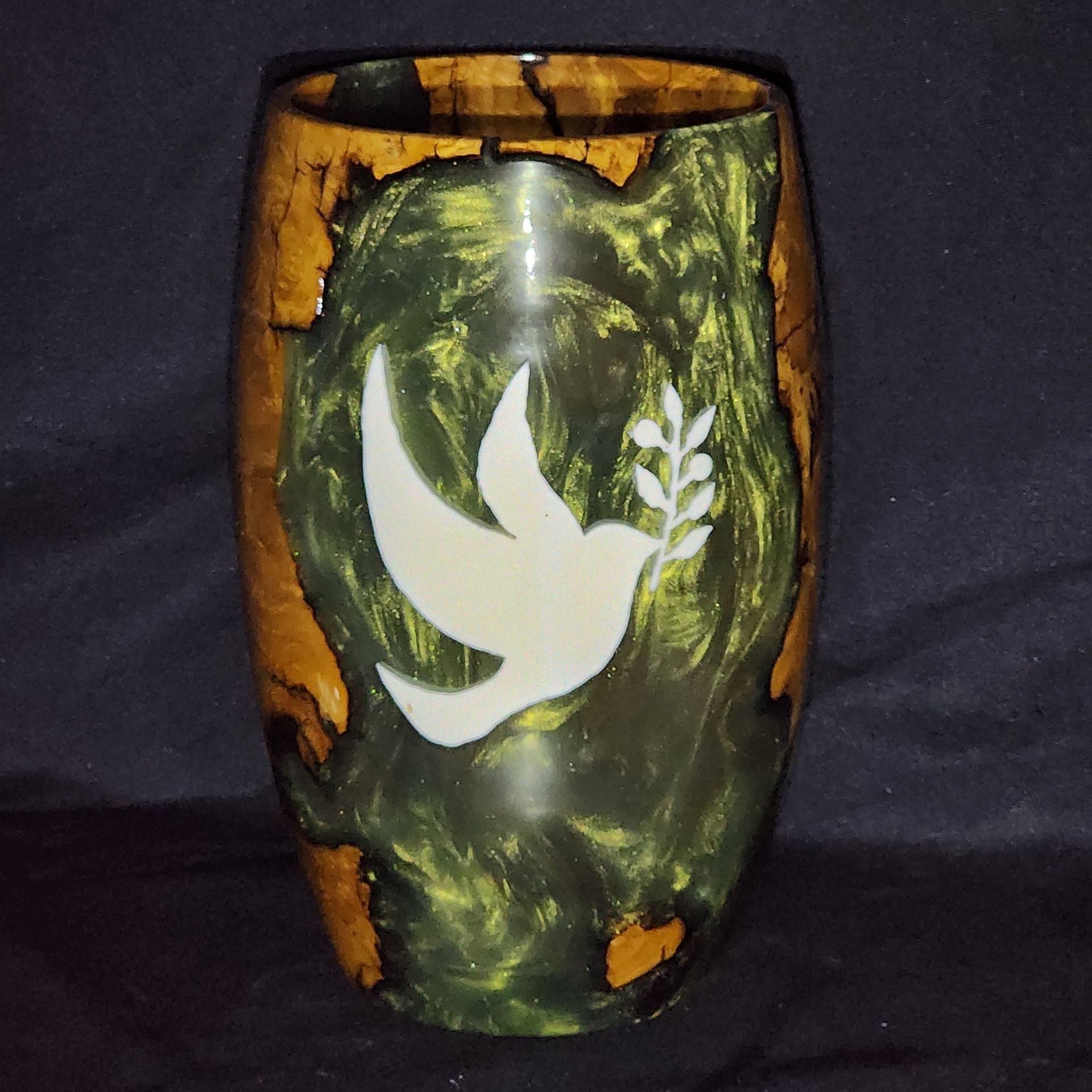 Wooden vase with a white dove holding an olive branch against green and gold epoxy resin.