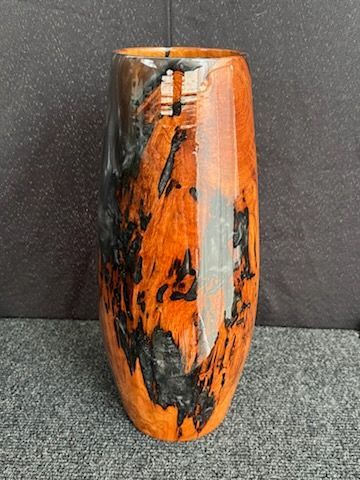 Tall wooden vase with a glossy finish, showcasing black and orange patterns.