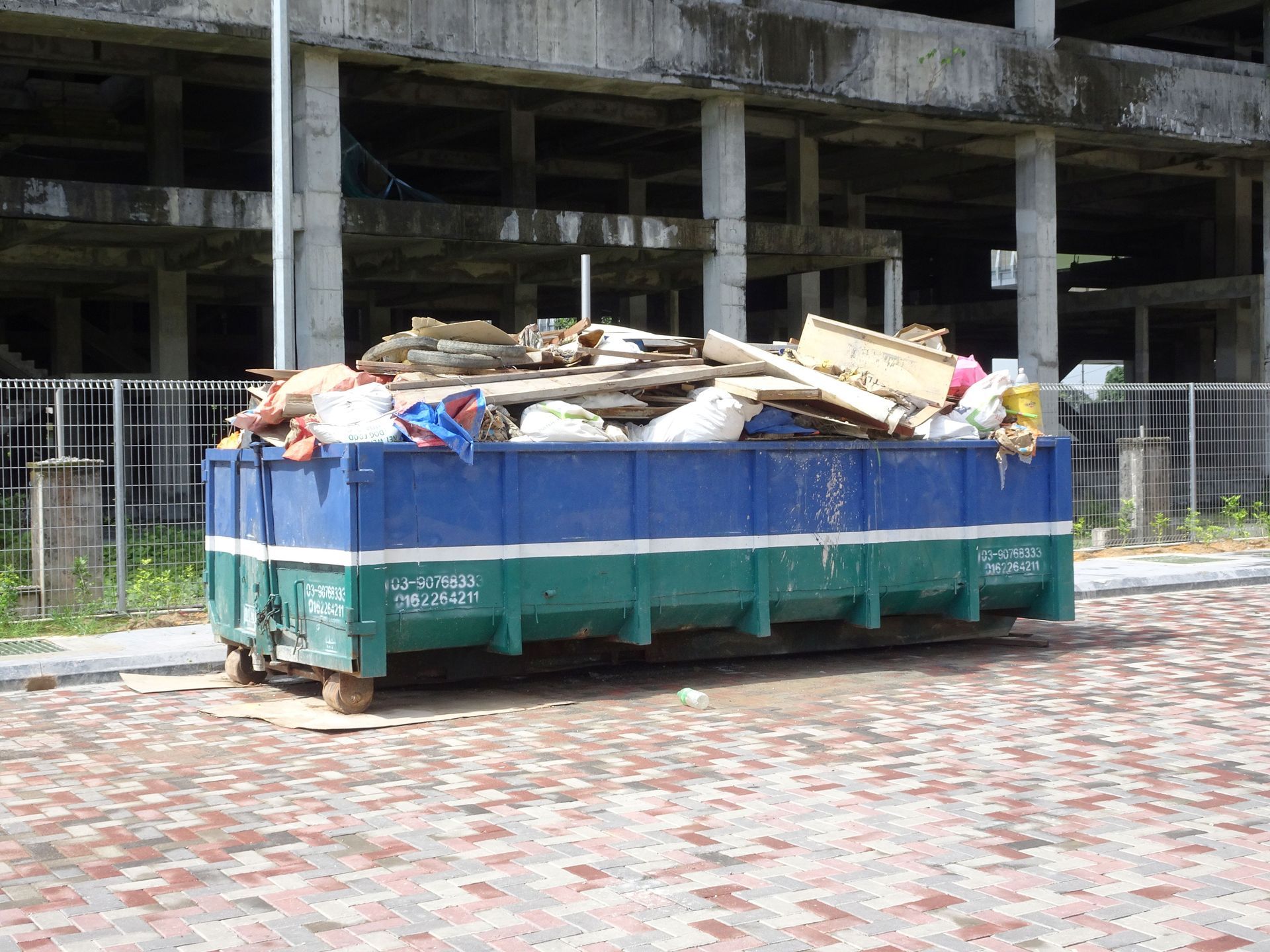 Roll-off dumpster rental bin collecting construction waste & unused materials at an active job site.