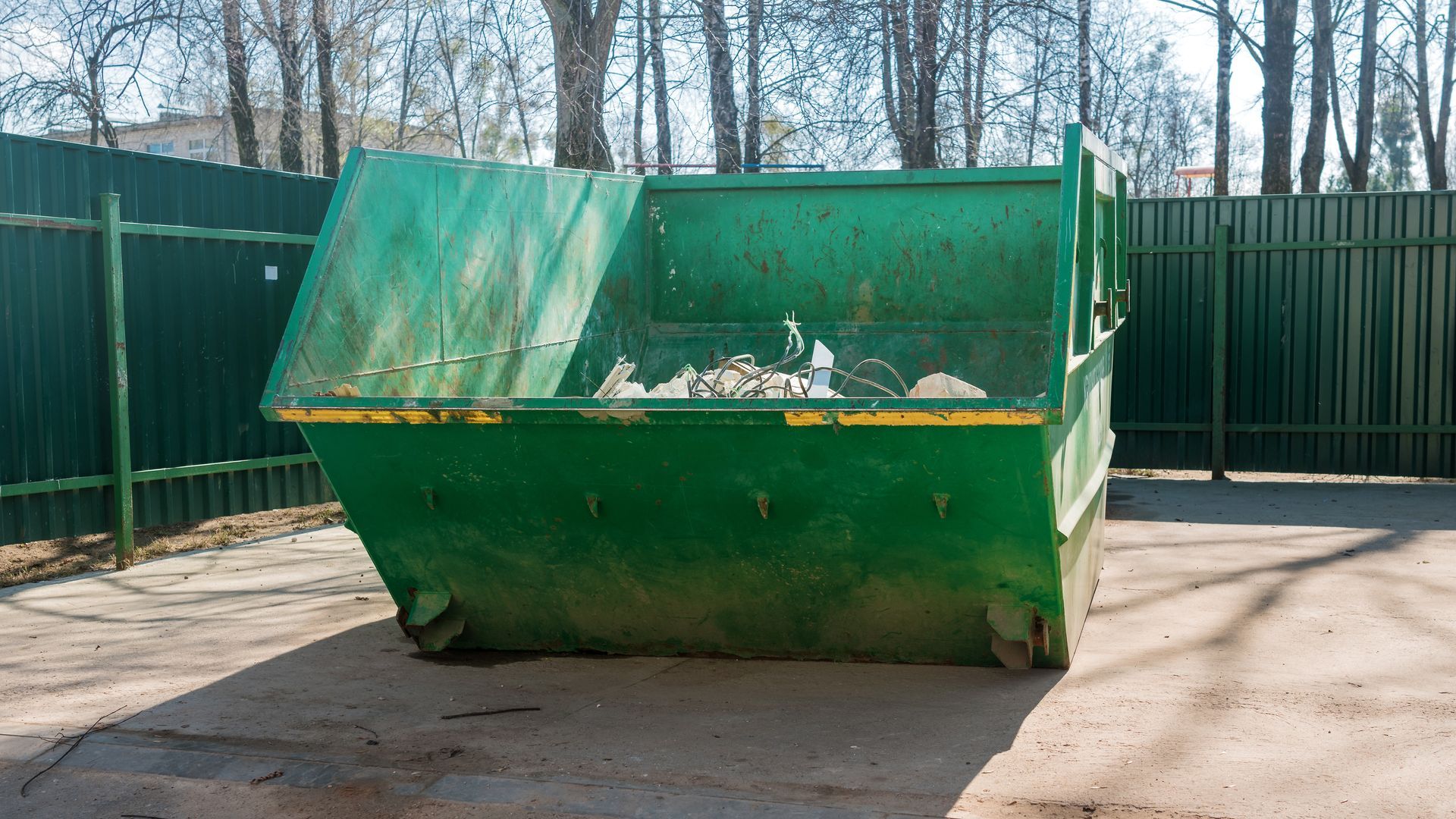 Large metal dumpster on site for efficient construction trash removal services.