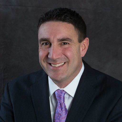 A man and a woman are sitting on a dock overlooking a lake.