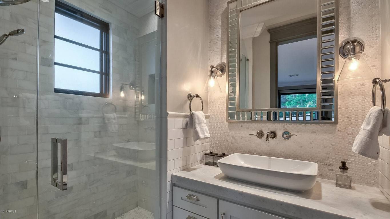 A bathroom with a sink , mirror and walk in shower.