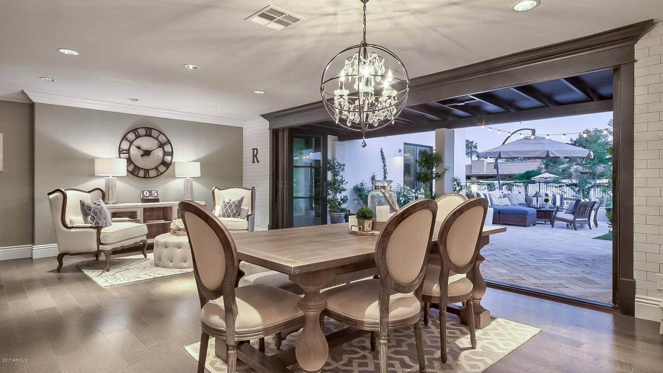 A dining room with a table and chairs and a clock on the wall.