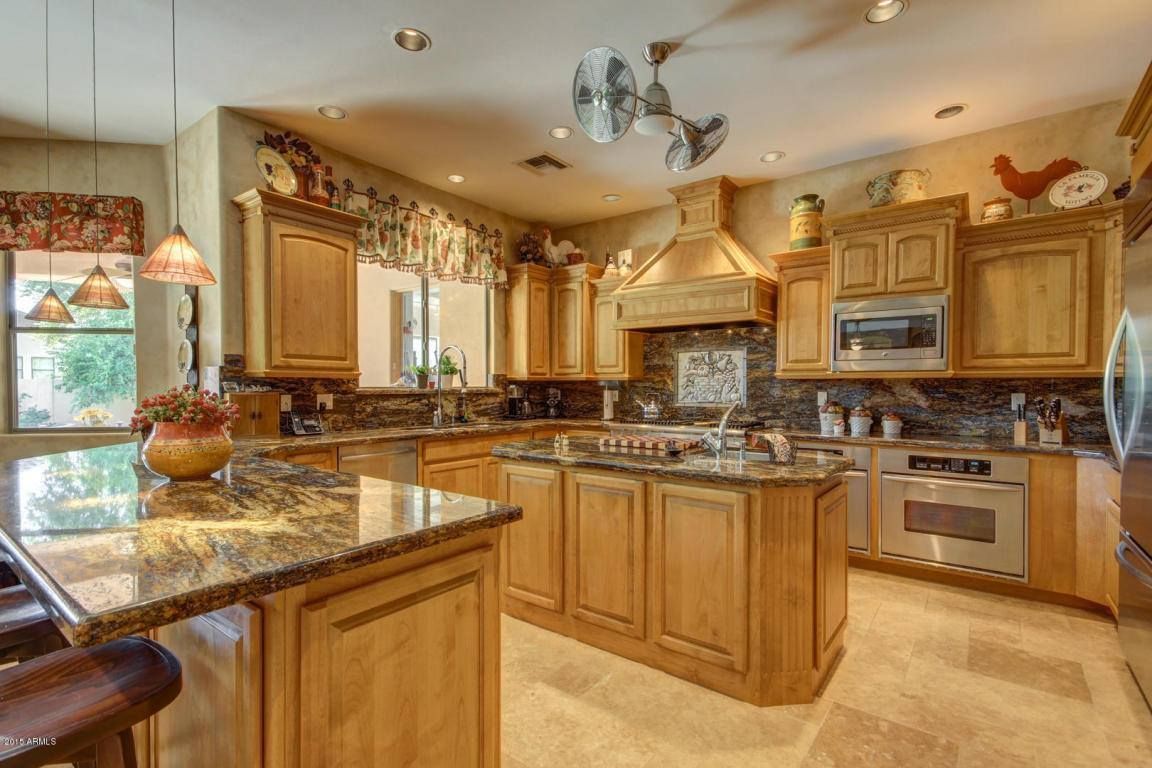 A kitchen with wooden cabinets , granite counter tops , stainless steel appliances and a large island.