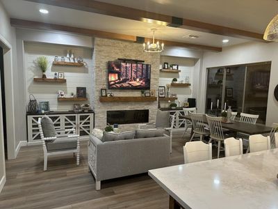A living room with a couch , chairs , a fireplace and a flat screen tv.