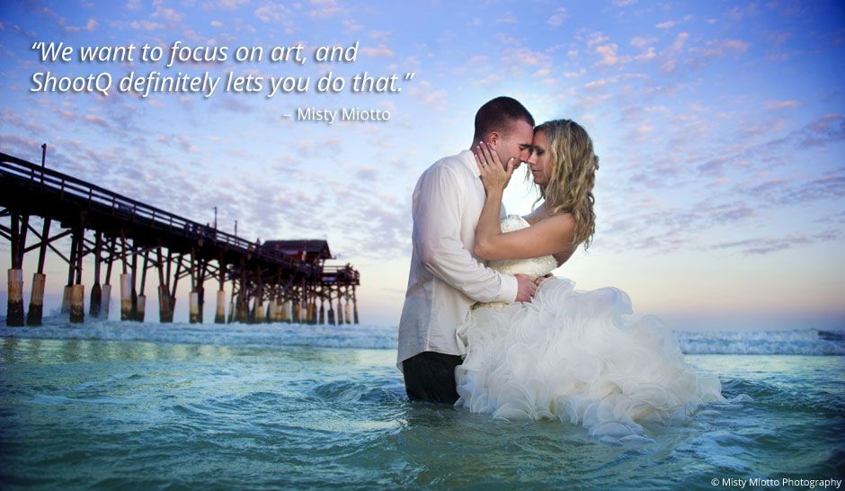 A bride and groom are kissing in the water near a pier.