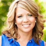 A woman in a blue shirt is smiling for the camera.