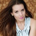 A woman with long hair is wearing a white and black dress and earrings.