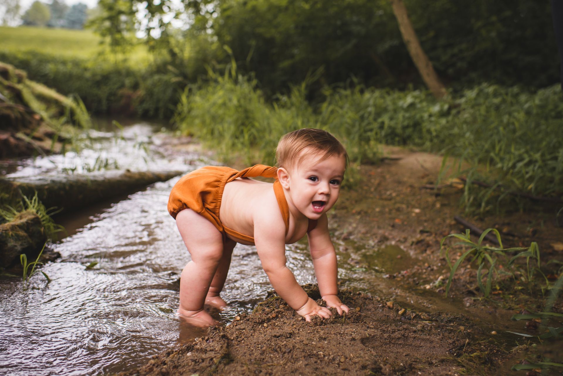 A baby is crawling in a stream of water.