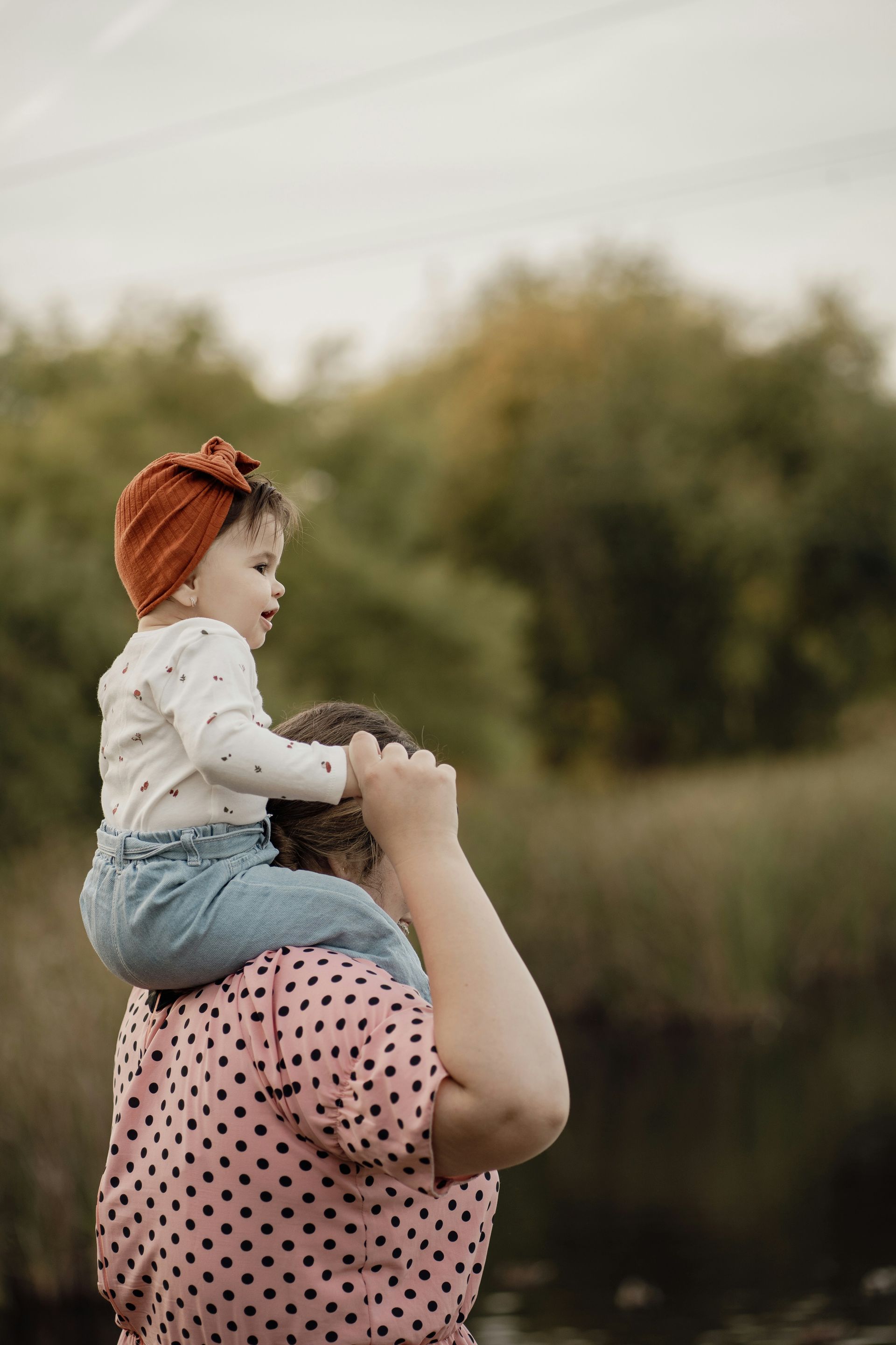 A woman is carrying a baby on her shoulders.