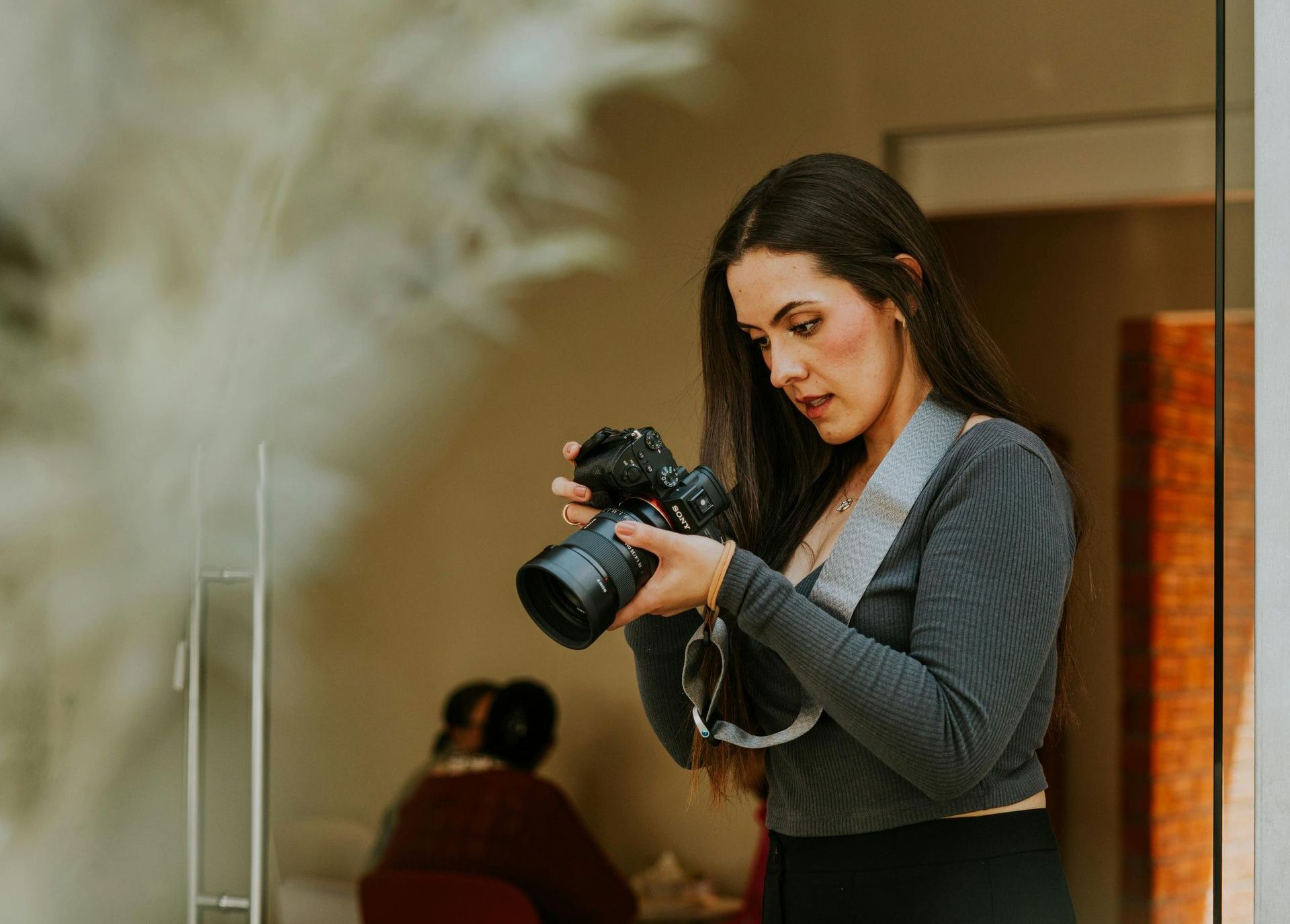 A woman is holding a camera in front of a glass door.