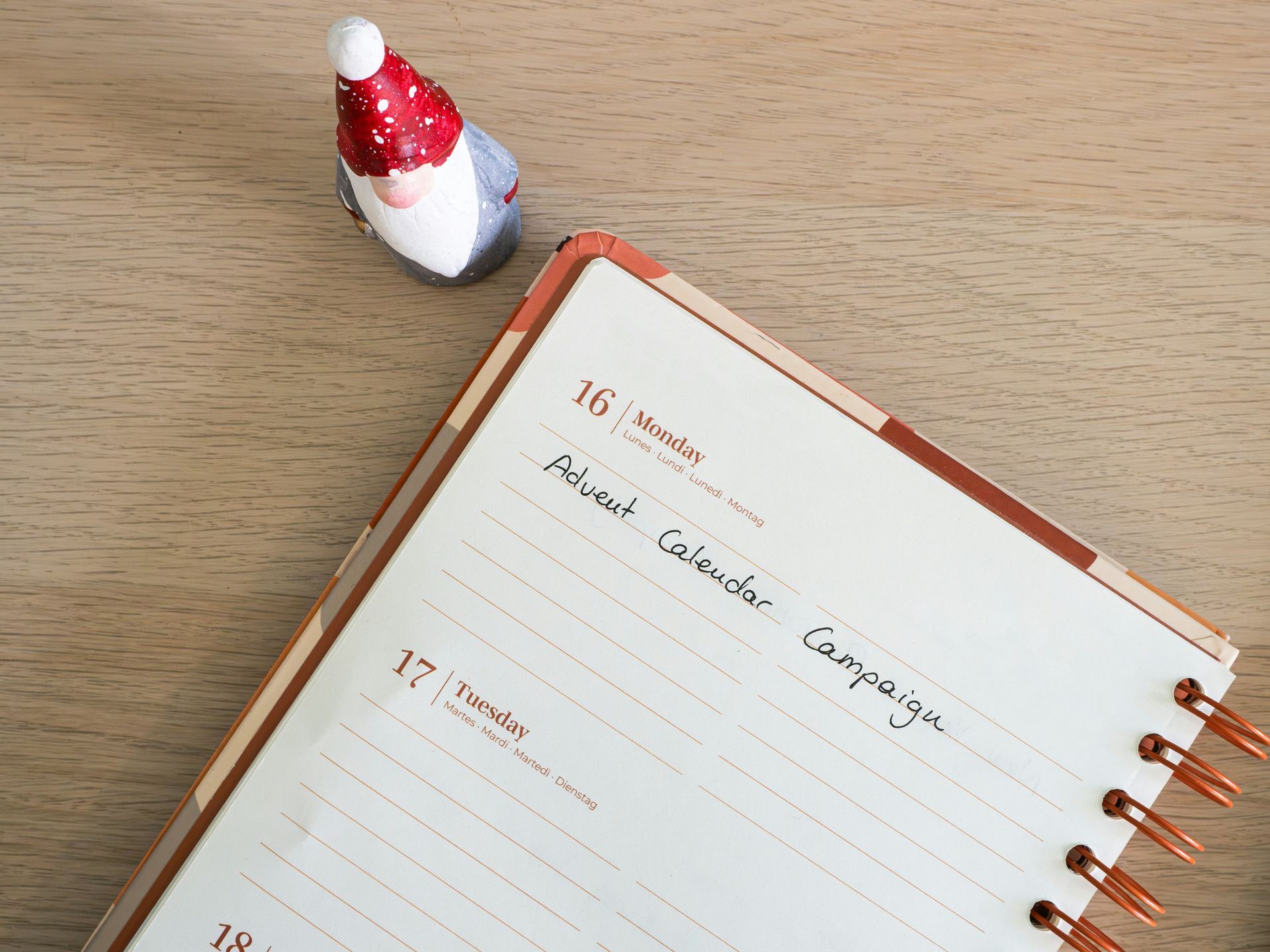 A christmas decoration is sitting next to a notebook on a wooden table.