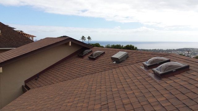 A roof with two skylights on it and a view of the ocean.