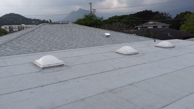 A roof with two skylights and a solar panel on it.
