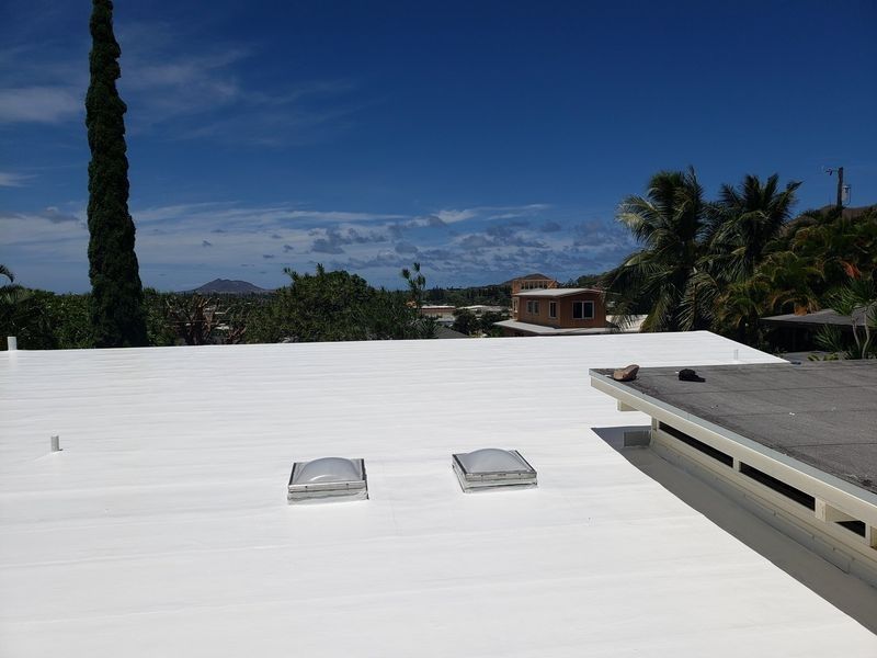 A white roof with two skylights on it.