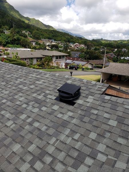 A roof with a vent on it and a mountain in the background.