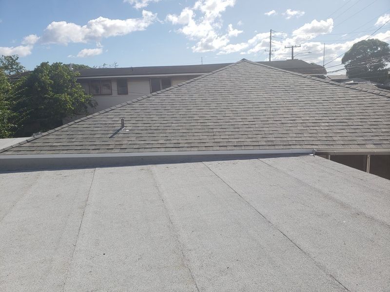 The roof of a house with a gray roof and a blue sky in the background.