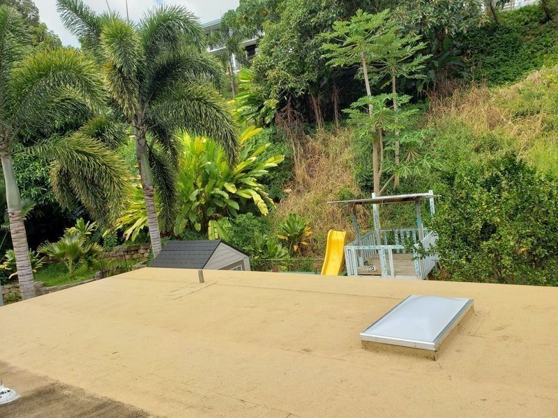 A roof with a skylight and a playground in the background.