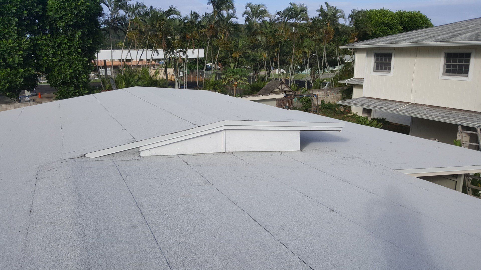 A white house with a white roof and trees in the background.