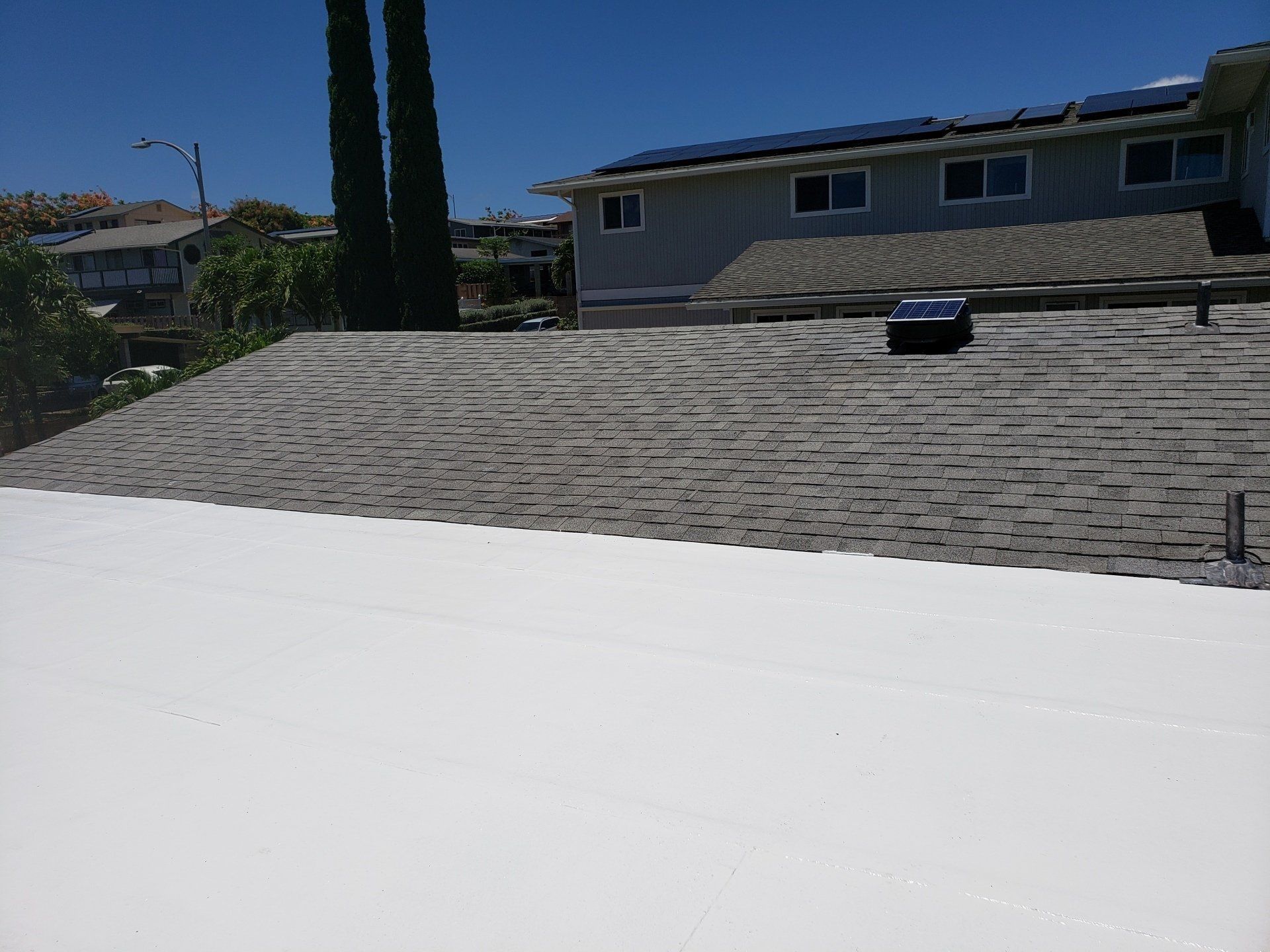 A roof with white roof and a house in the background.