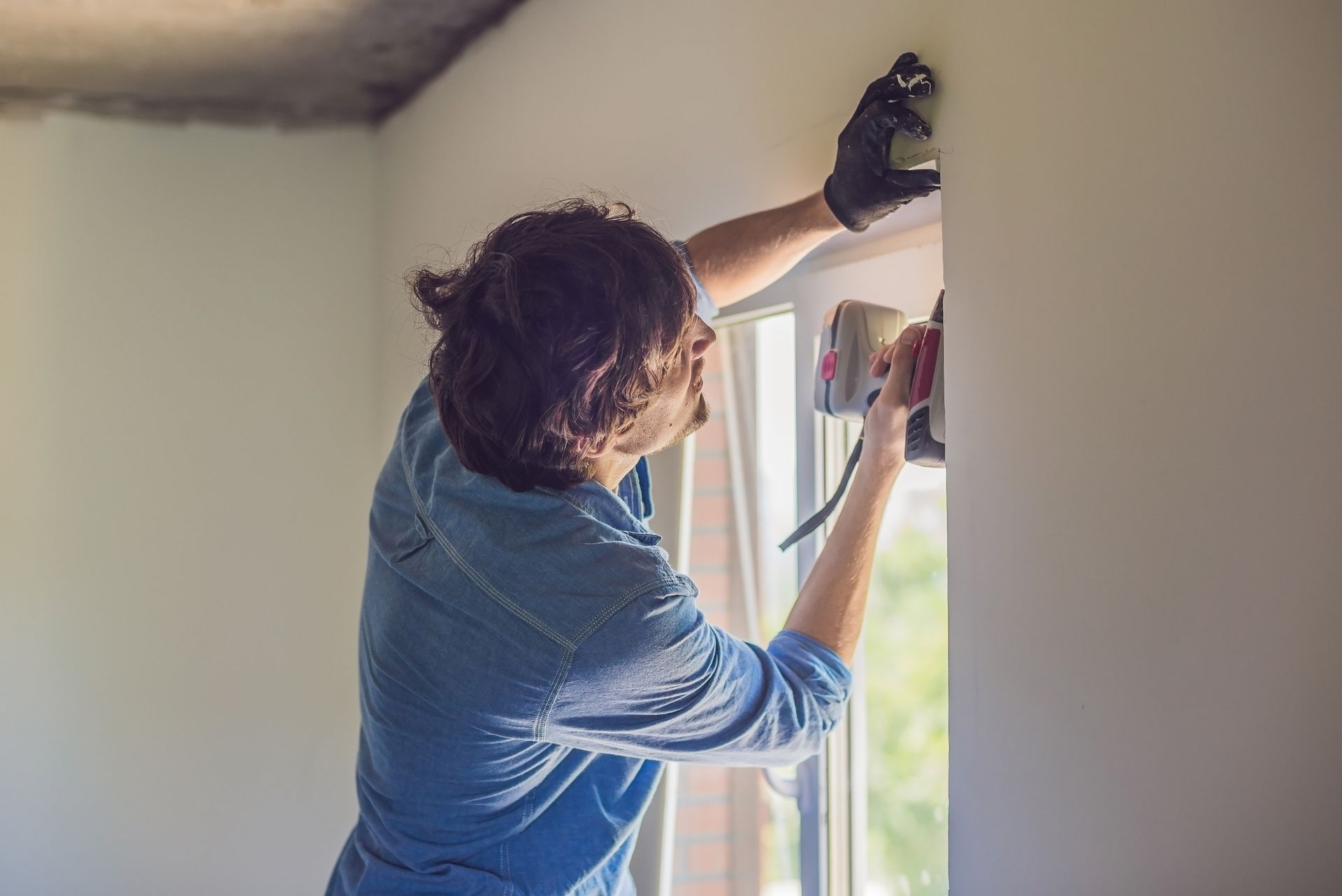 A man is installing a window with a drilling tool.
