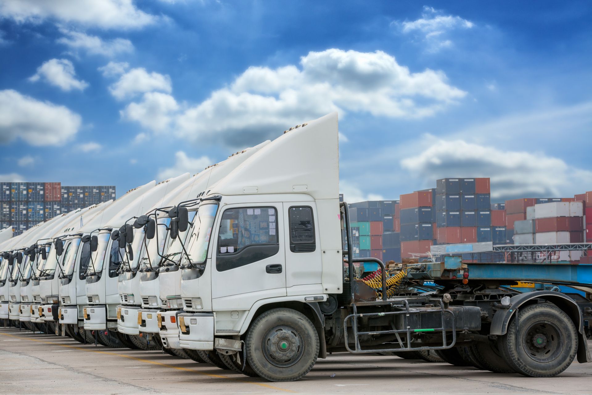 A row of semi trucks parked next to each other in a parking lot.