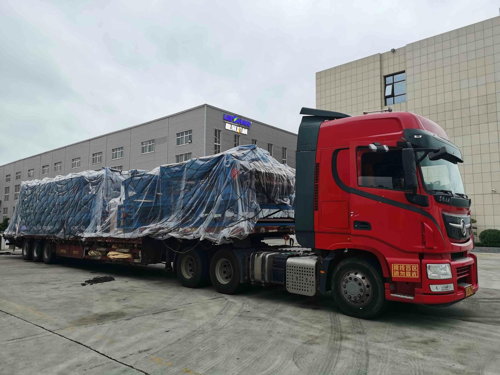A red semi truck is parked in front of a building.