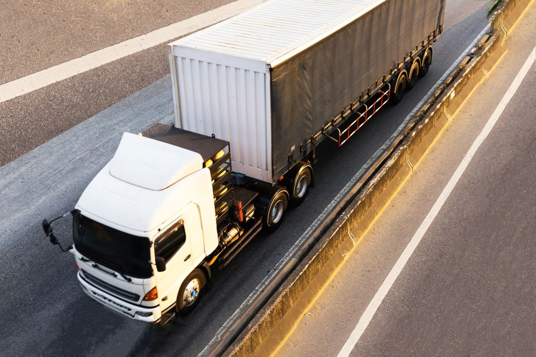 White semi-truck driving on a highway.