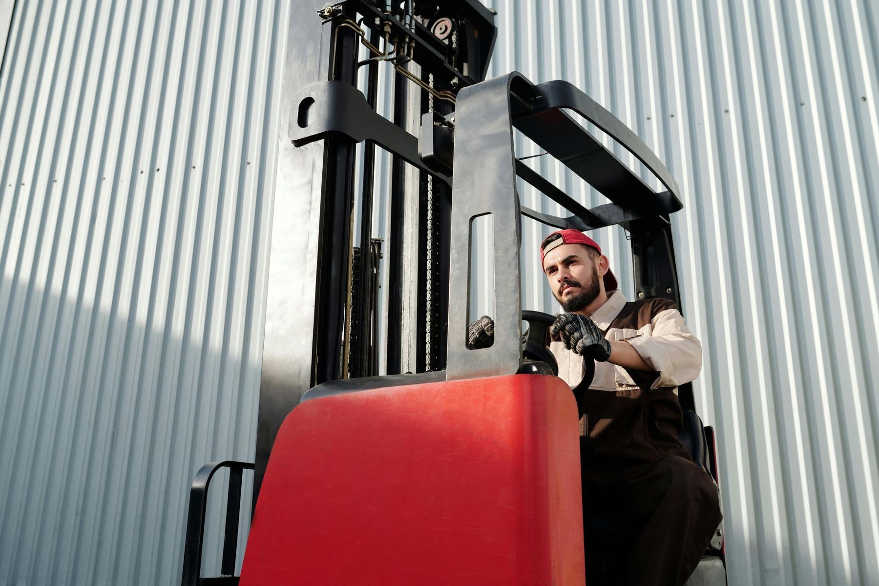 A man is driving a forklift in front of a building.