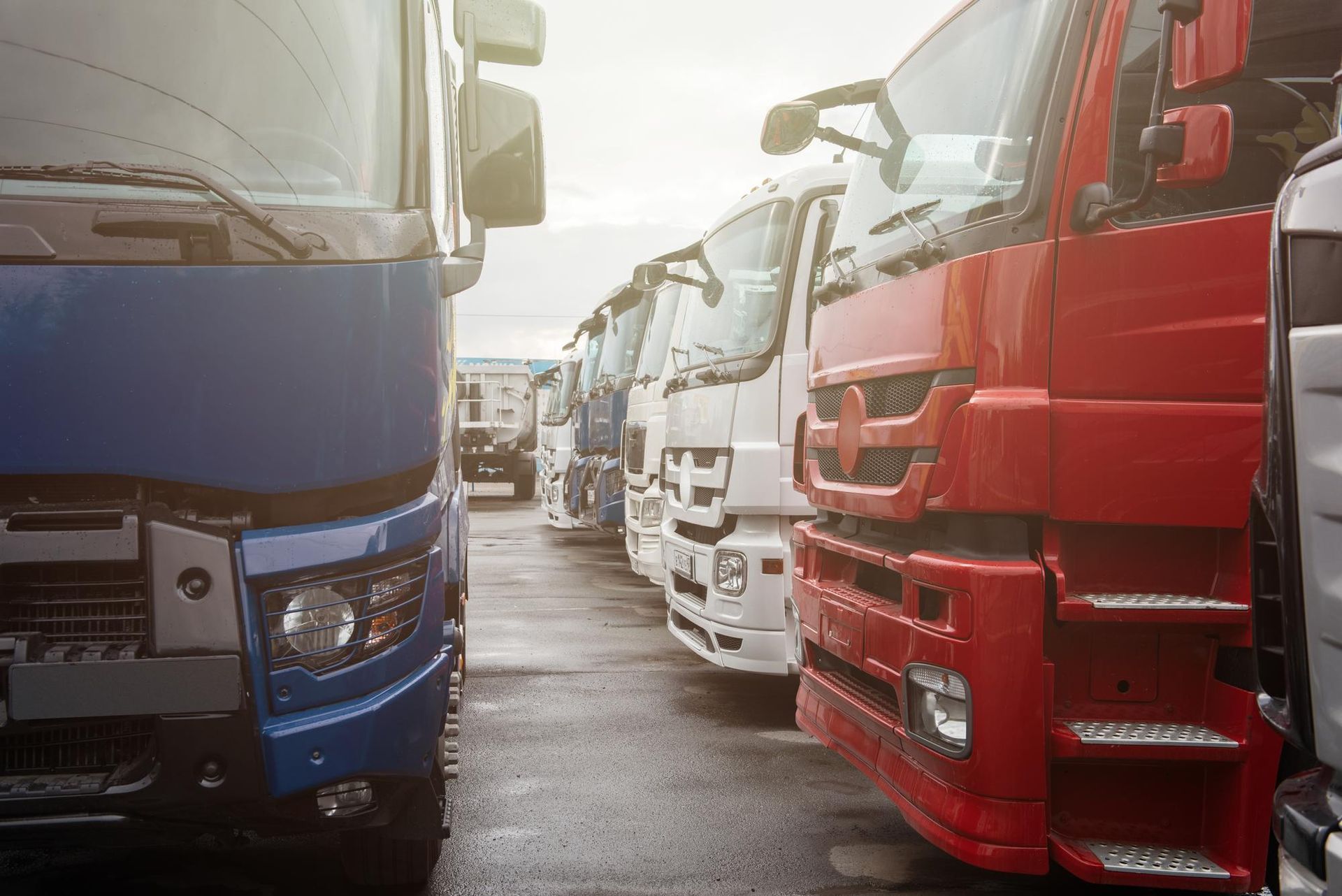 A row of semi trucks parked next to each other in a parking lot.