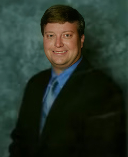 A man in a suit and tie is smiling for the camera