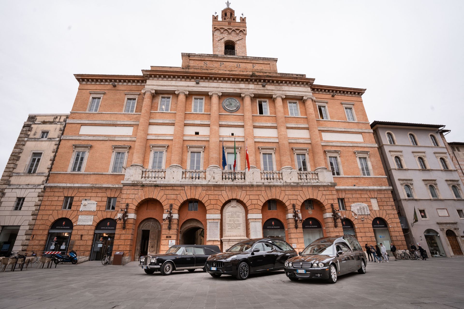 Tre auto sono parcheggiate davanti a un grande edificio in mattoni.