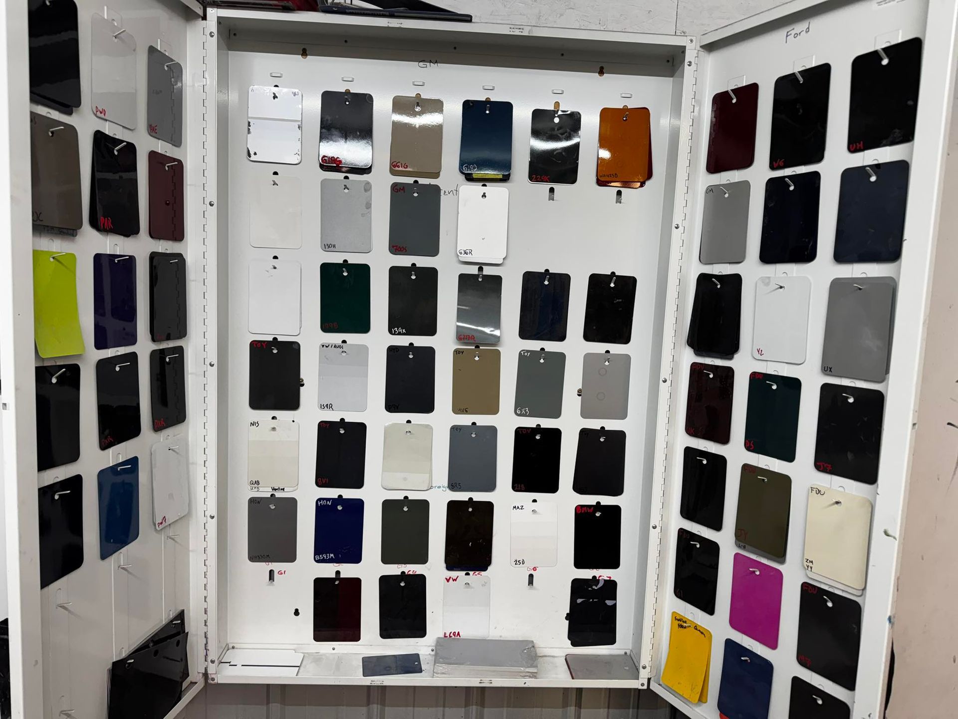 A display board holding numerous small color sample swatches in various shades, arranged in columns and rows.