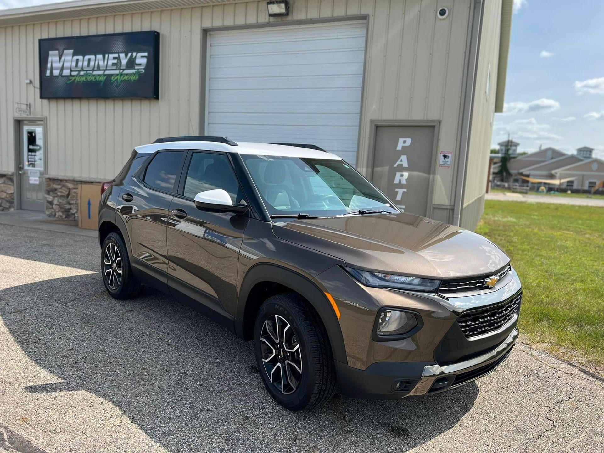 A brown and white Chevrolet Trailblazer parked in front of a building with a 