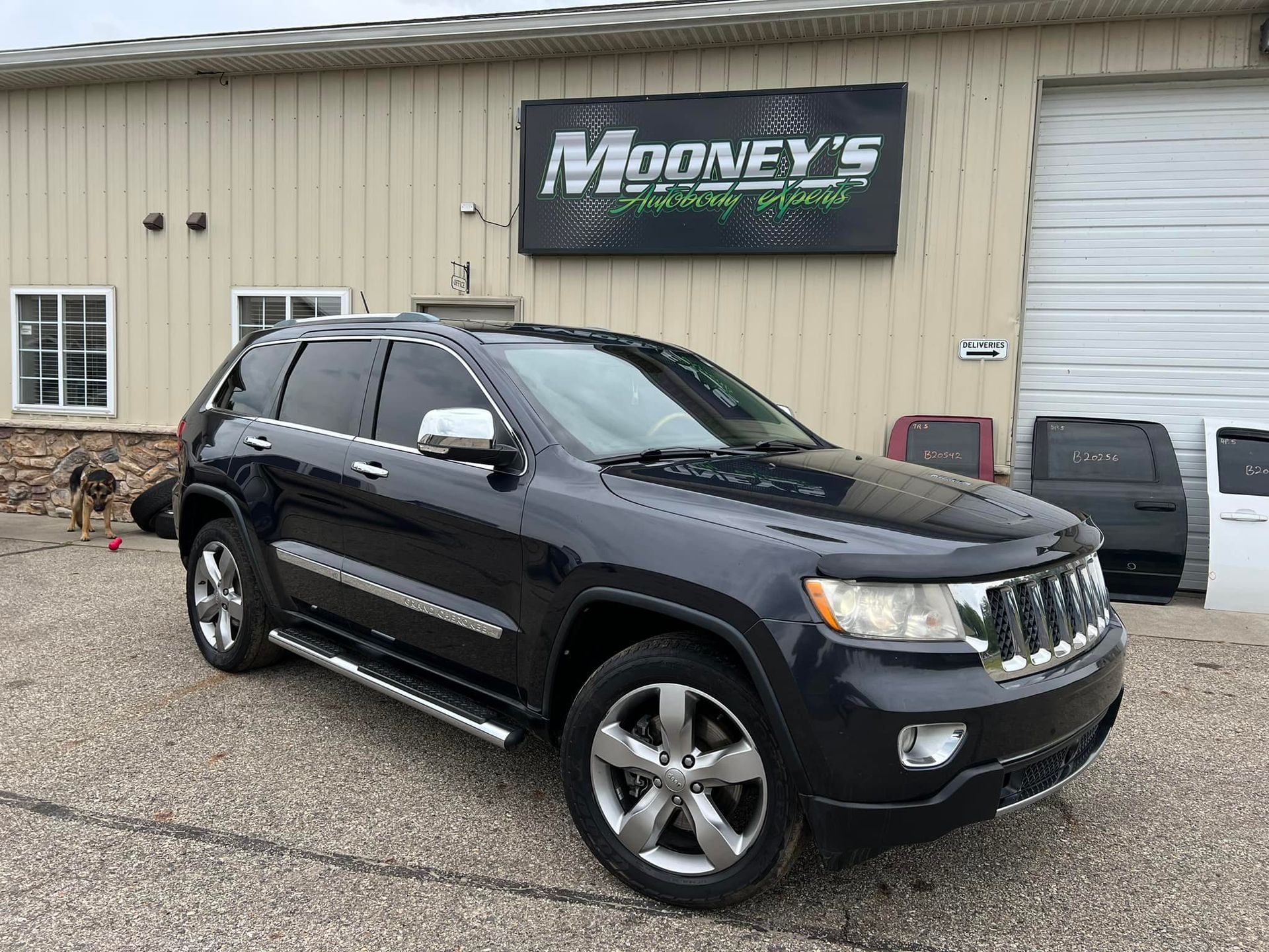 A black Jeep Grand Cherokee parked in front of a metal-sided building with a 