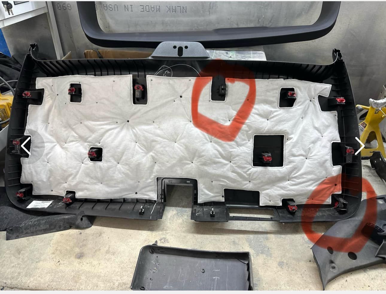 Automotive interior trim panel with insulation material, showing mounting clips, with two areas marked in red.