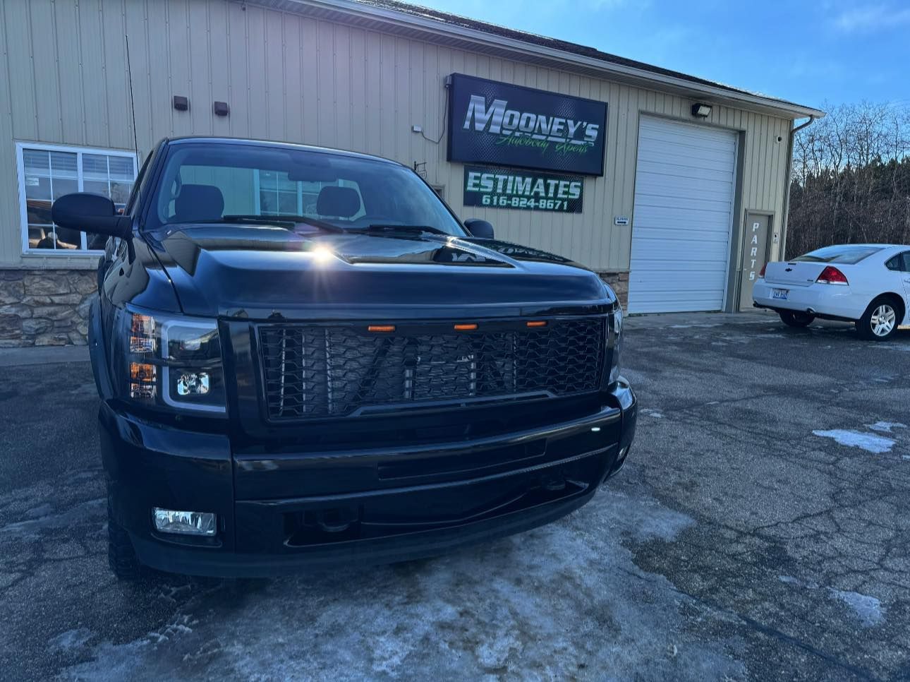 A black pickup truck parked in front of a building with a sign that reads 