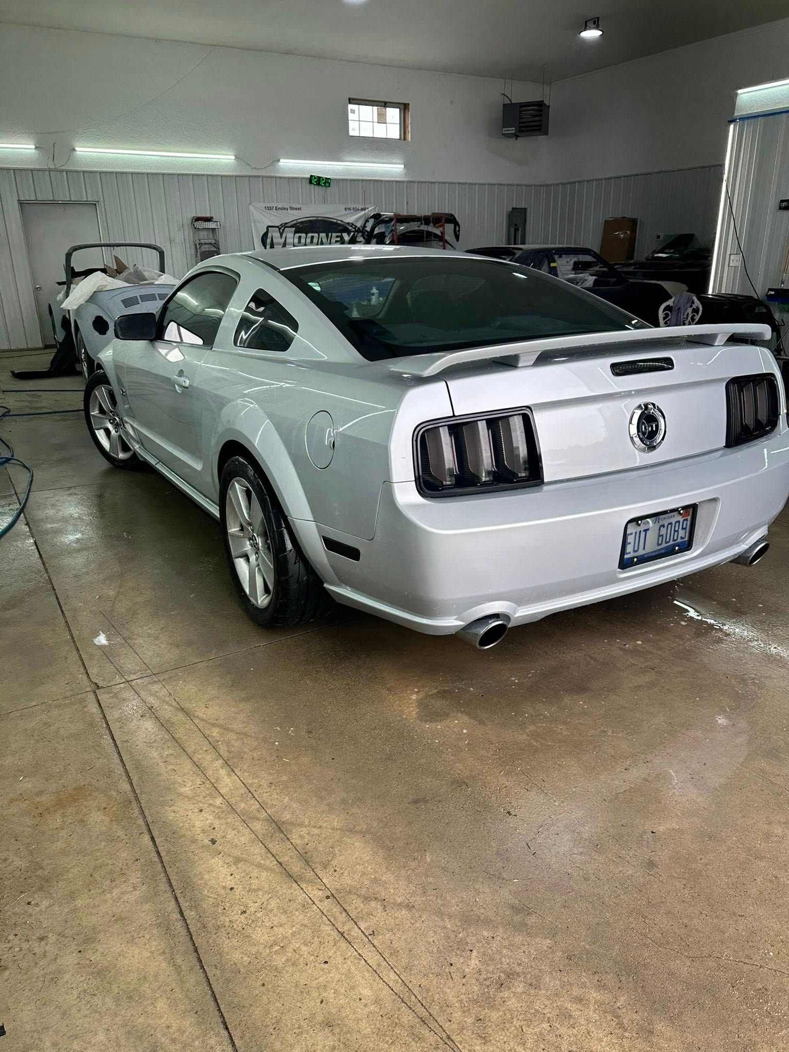 A silver Ford Mustang parked in a garage, shown from the rear three-quarter view.