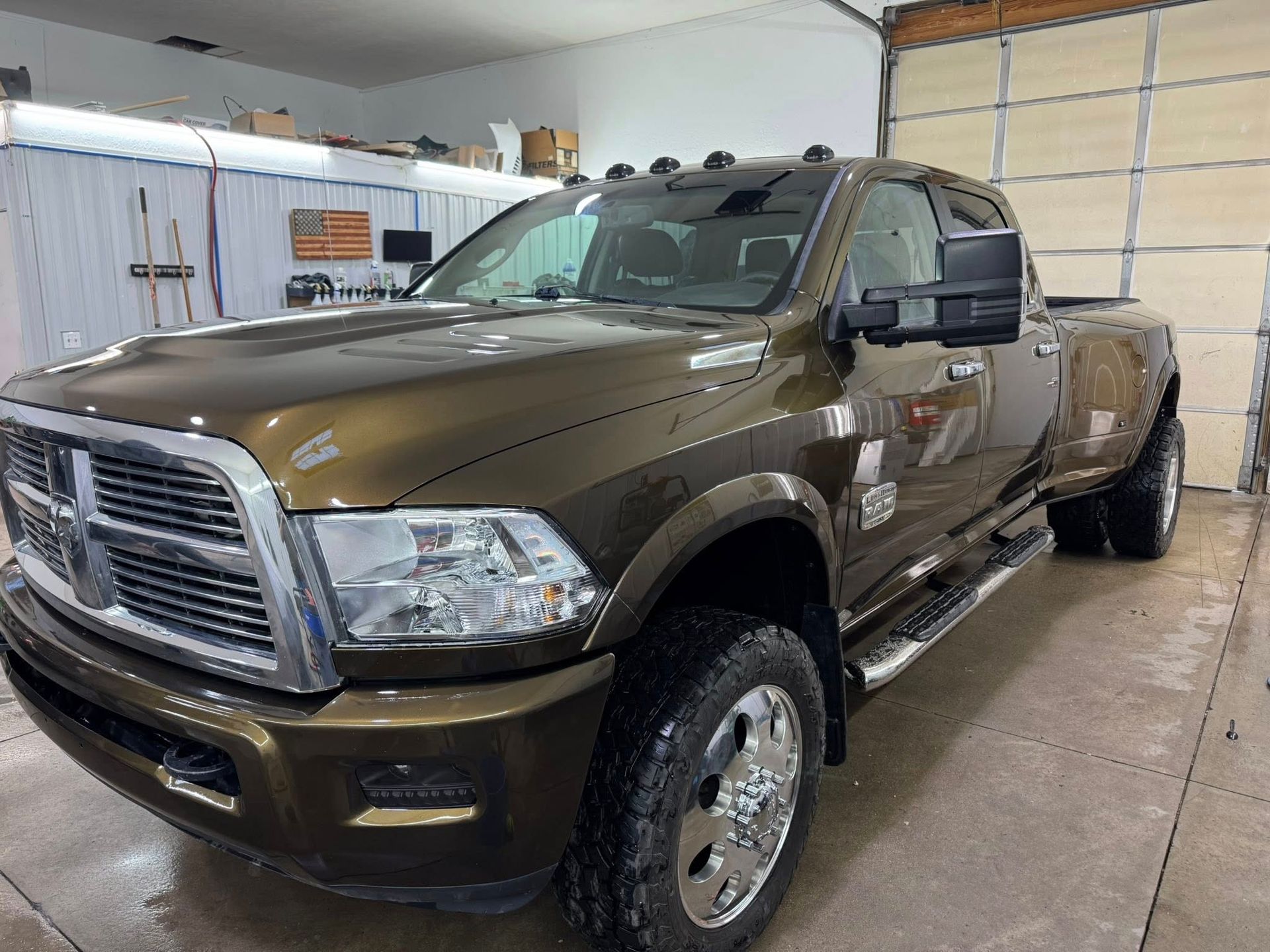 A metallic brown RAM dually pickup truck parked inside a garage.