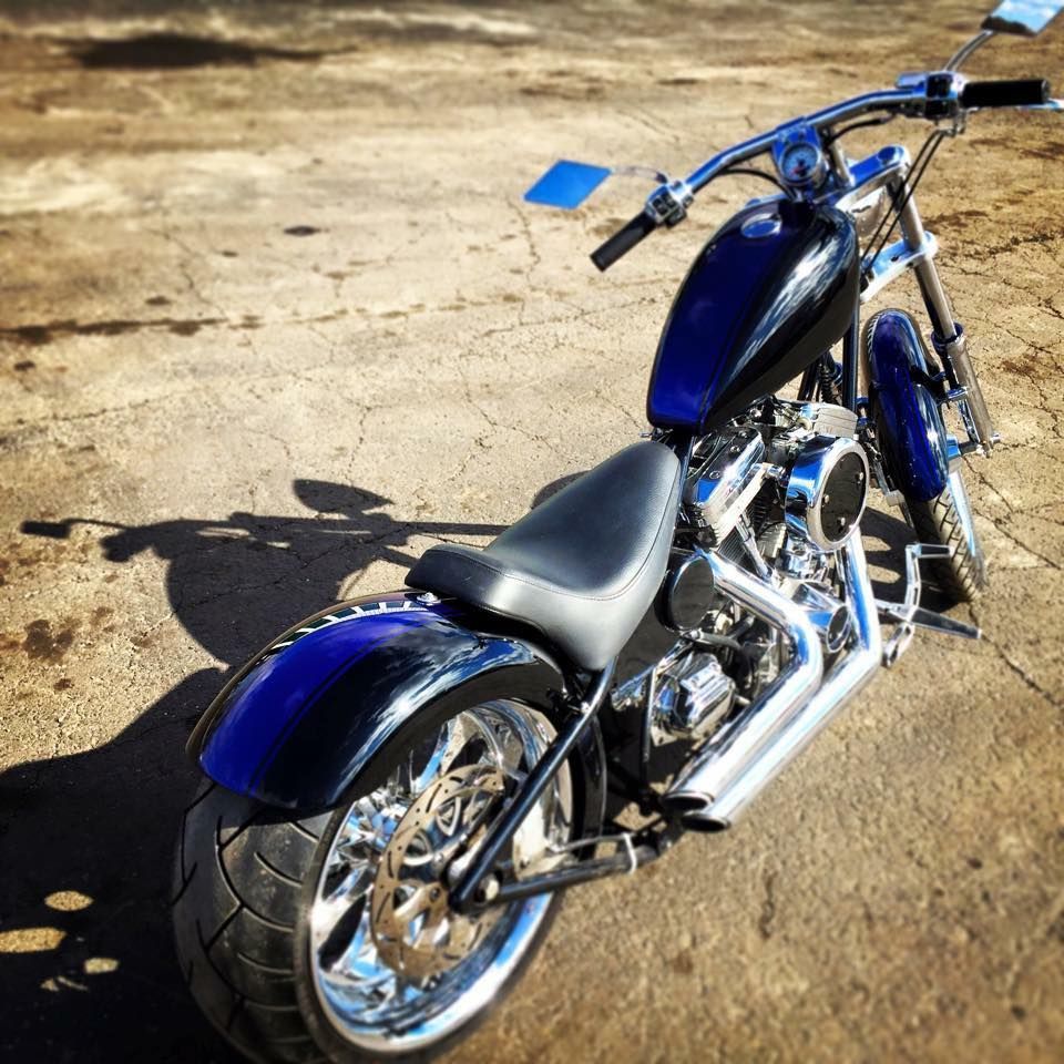 A blue and black custom chopper motorcycle parked on a weathered concrete surface.