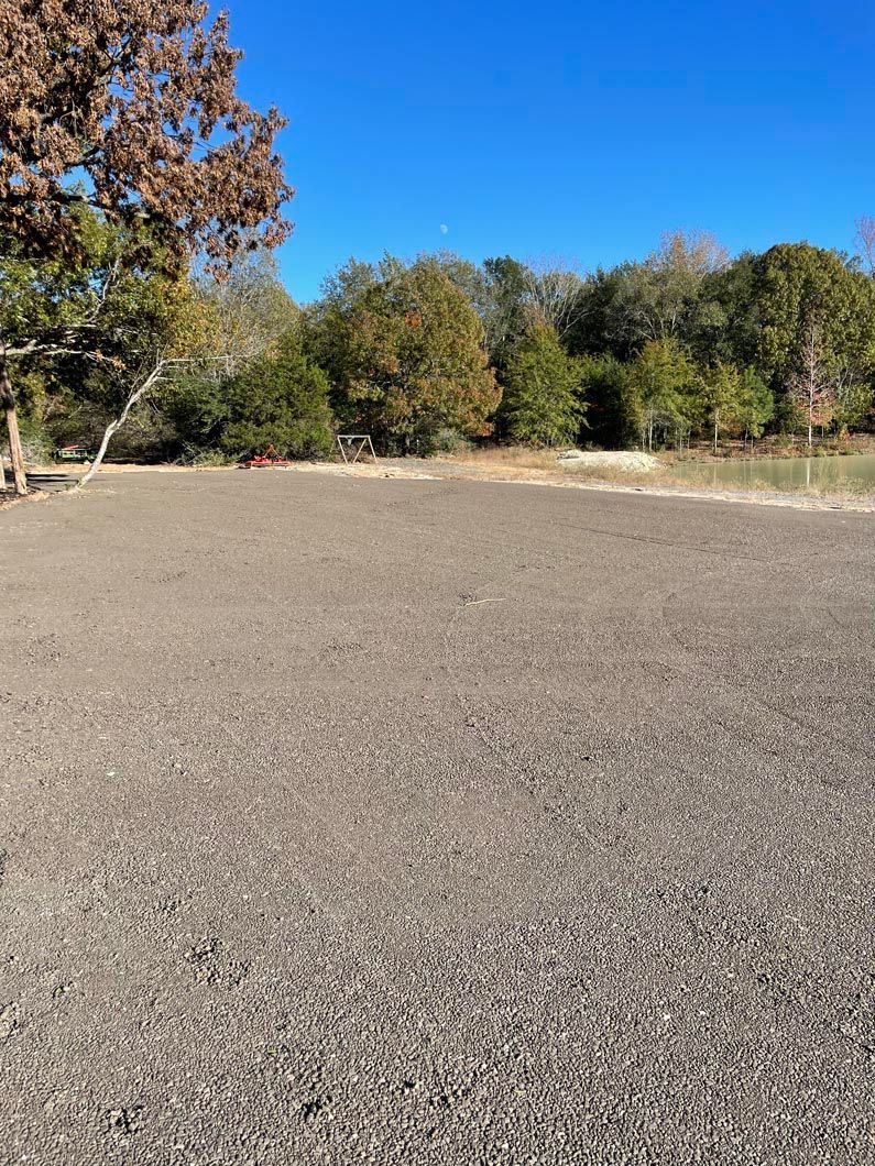 A large empty field with trees in the background on a sunny day.
