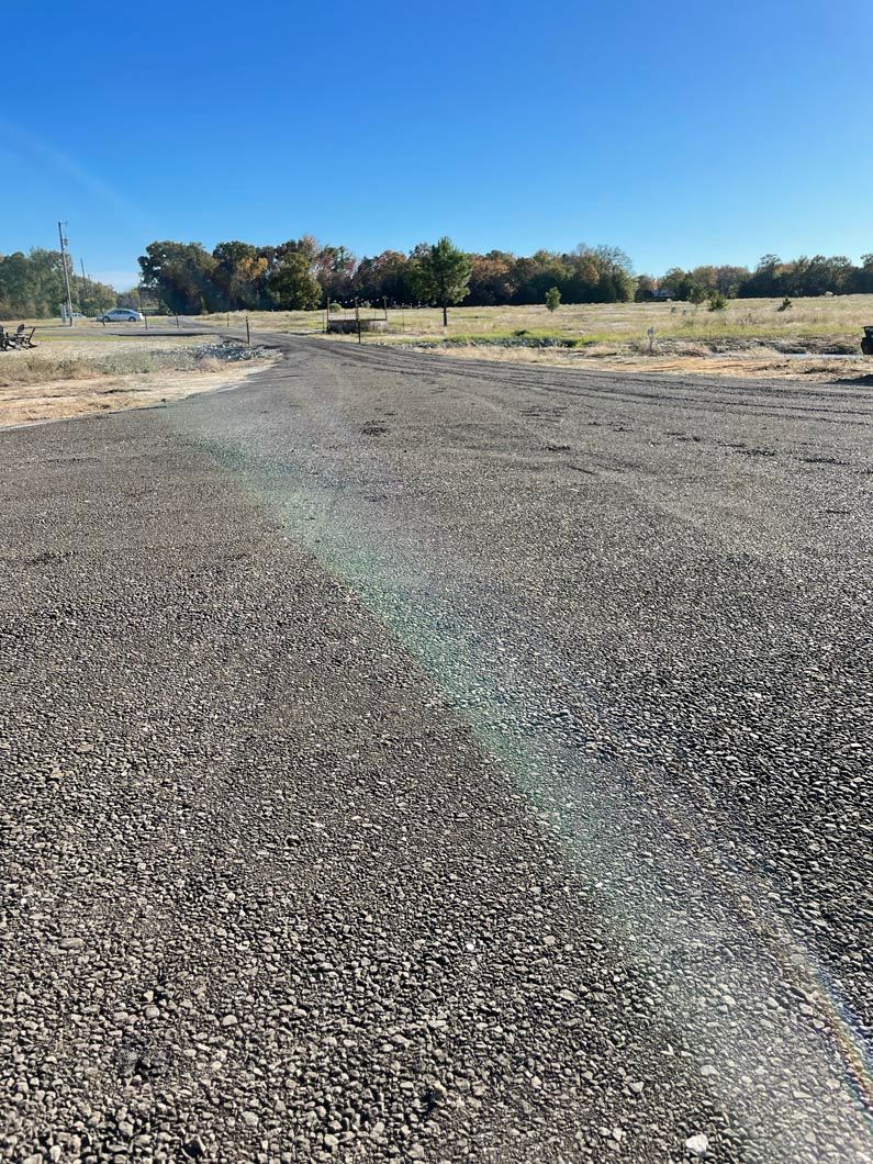 A gravel road with trees in the background on a sunny day.