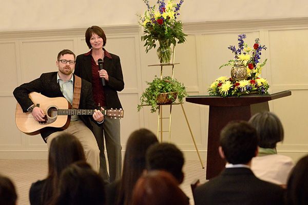 a man playing a guitar and a woman singing in front of a crowd