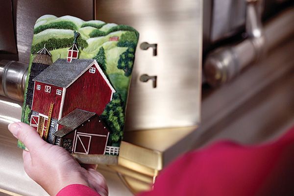 a person is holding a coaster with a barn on it