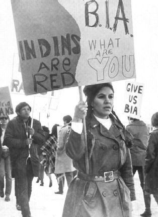 A woman holding a sign that says indians are red