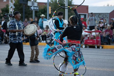 A man is playing a drum while a woman is dancing with hula hoops.