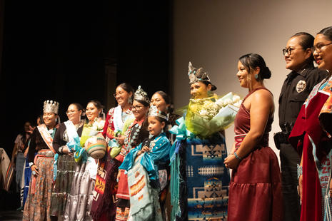 A group of women standing on a stage with flowers in their hands